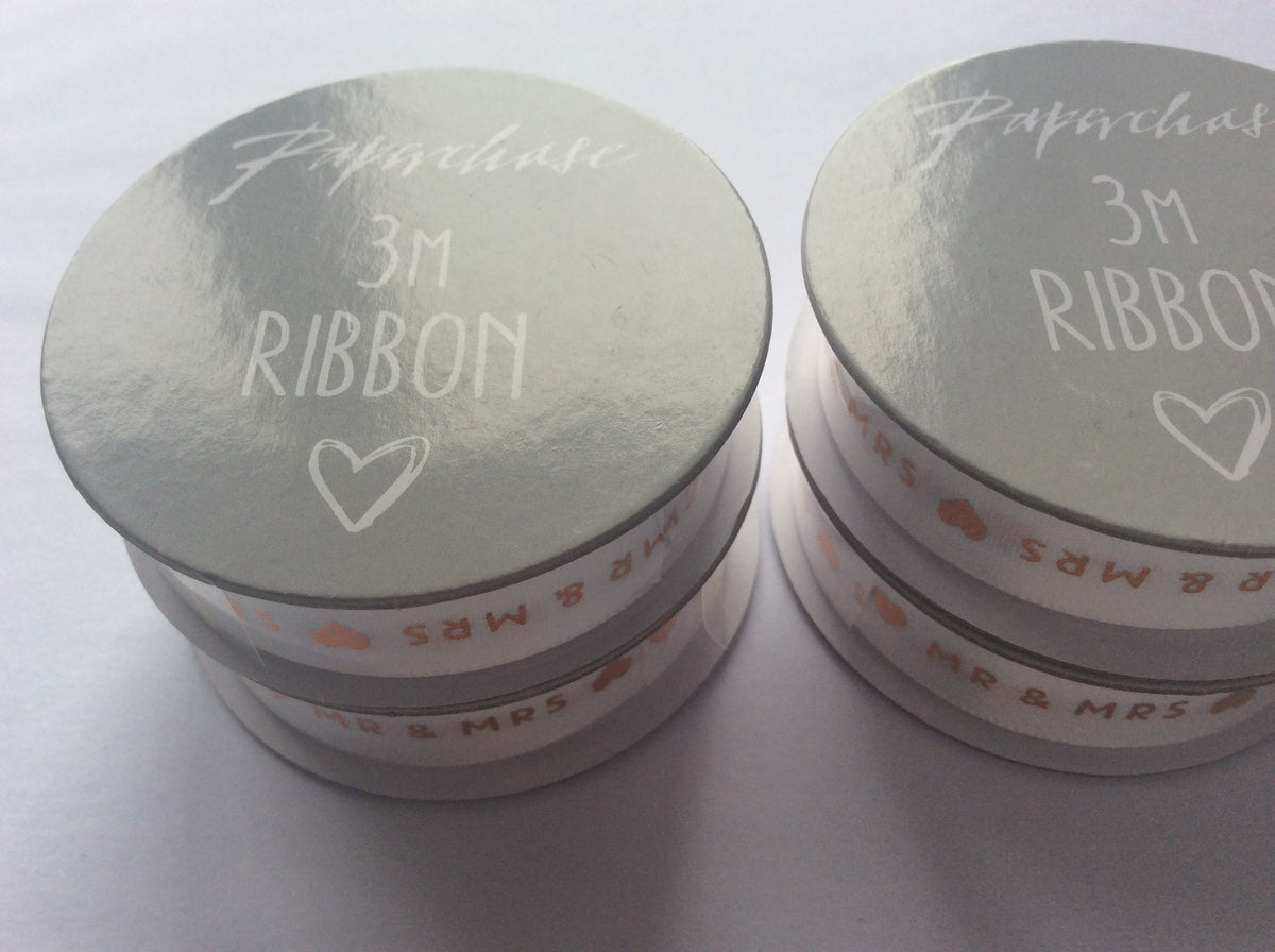 Close-up of white ribbon with gold Mr and Mrs lettering and heart motifs