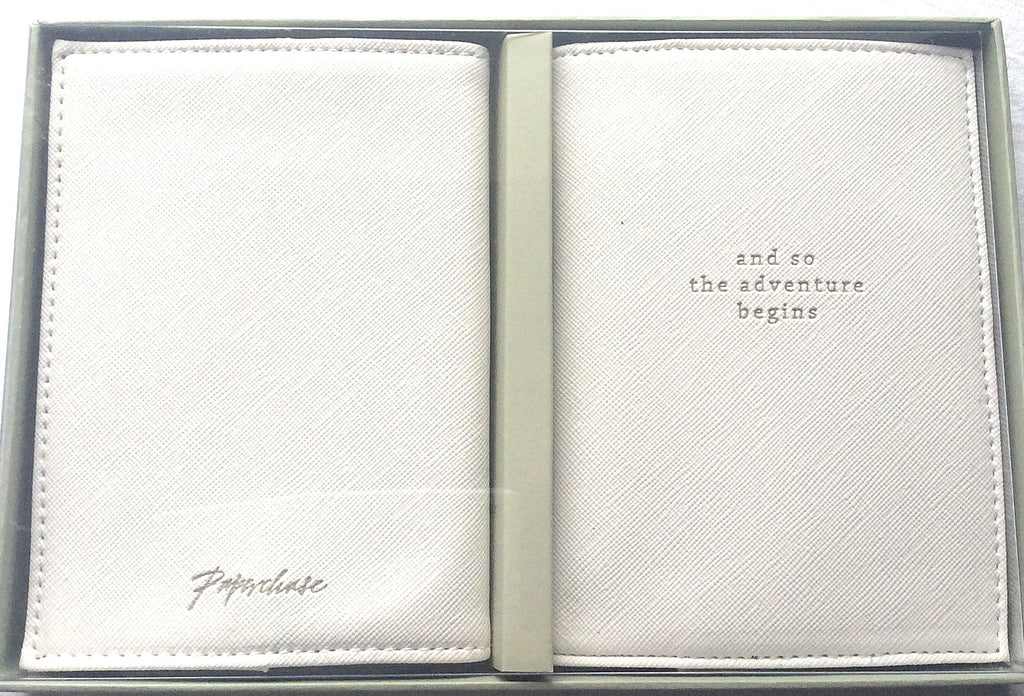Close view of two light-coloured textured passport holders with decorative wording