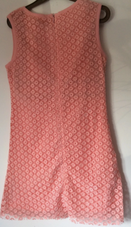 A sleeveless coral pink lace dress hanging on a dark hanger against a plain light background.
