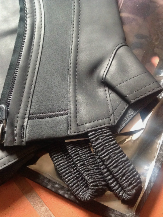 Close-up of the black ProChaps Competition leather half chaps logo and stitching