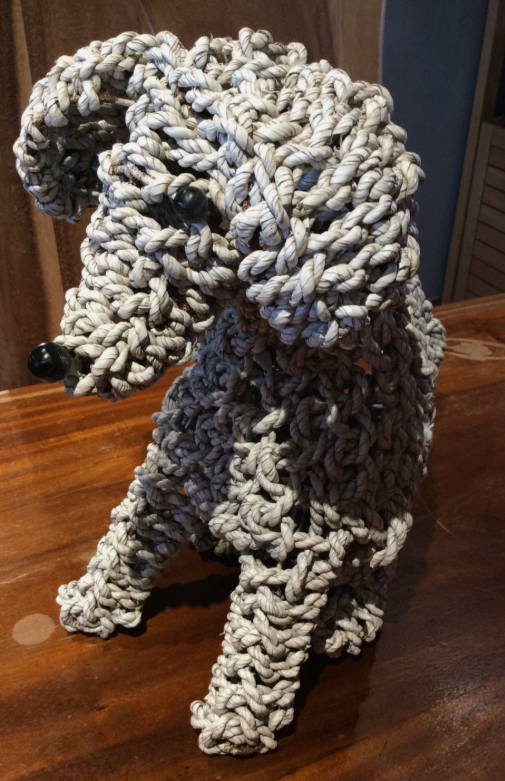 Handmade rope dog sculpture from Bali, front view showing handmade natural rope body on a wooden surface